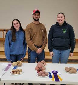 One potato, two potato: 4-H members pose with their award-winning spuds. Pictured are Nicole Non with her Reserve Grand Champion potato entry, left; Penn State Extension agronomy educator Zachary Curtis; and  Channing Rutledge with her Grand Champion potato entry.